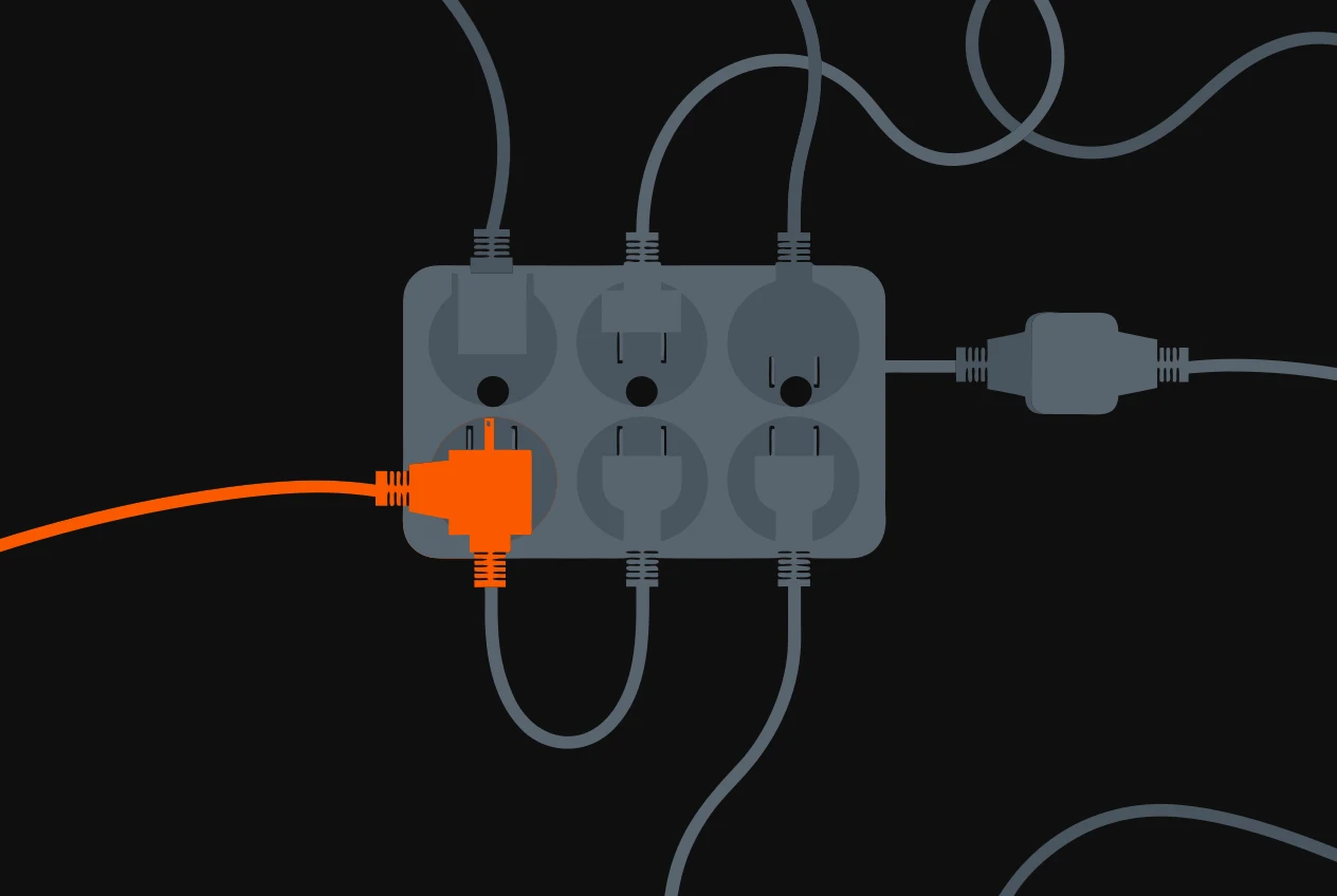 An overloaded power board with plugs crammed into every socket and one adapter daisy-chained off it, a single plug orange.