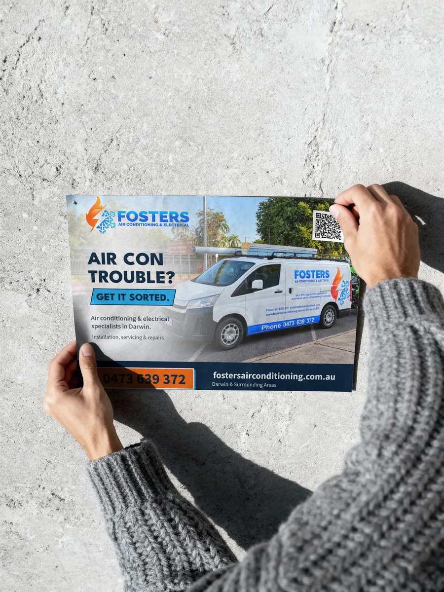 Example printed poster for a Darwin air conditioning and electrical business, with the van, phone number and a QR code, held up against a wall.